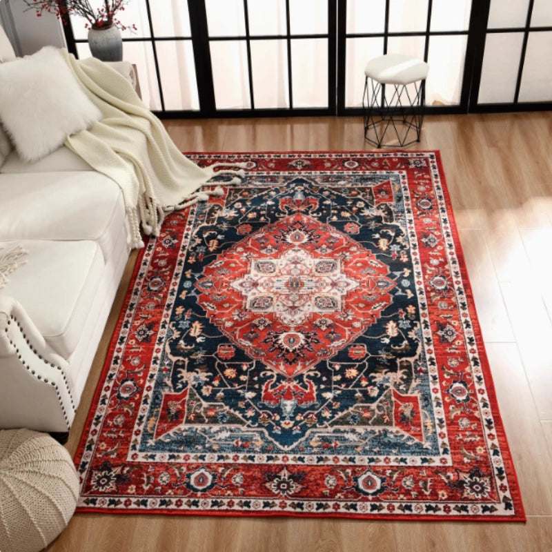 Tapis à motif géométrique rétro pour salon Nesty - Motif médaillon rouge et bleu marine à bordure florale dans un salon lumineux