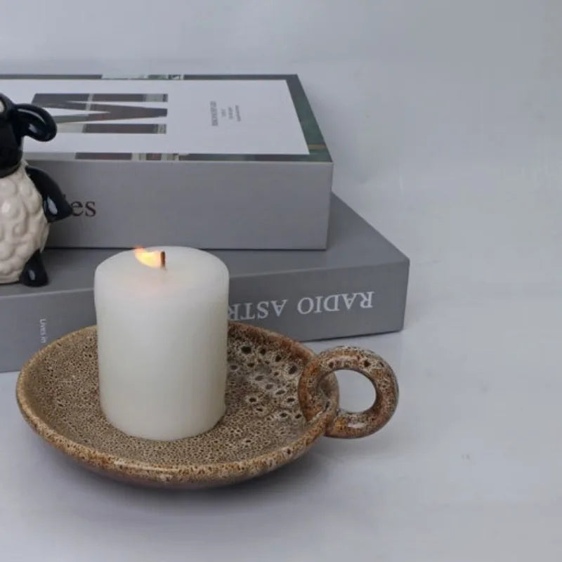 Bougeoir en céramique vieillie Nesty - Coupelle bougeoir glaçurée marron-beige à anse, bougie pilier allumée, figurine mouton en arrière-plan