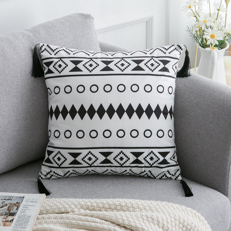 Housse de coussin en polyester satiné Nesty - Motif ethnique à losanges et cercles noirs, coins à glands, sur un canapé gris